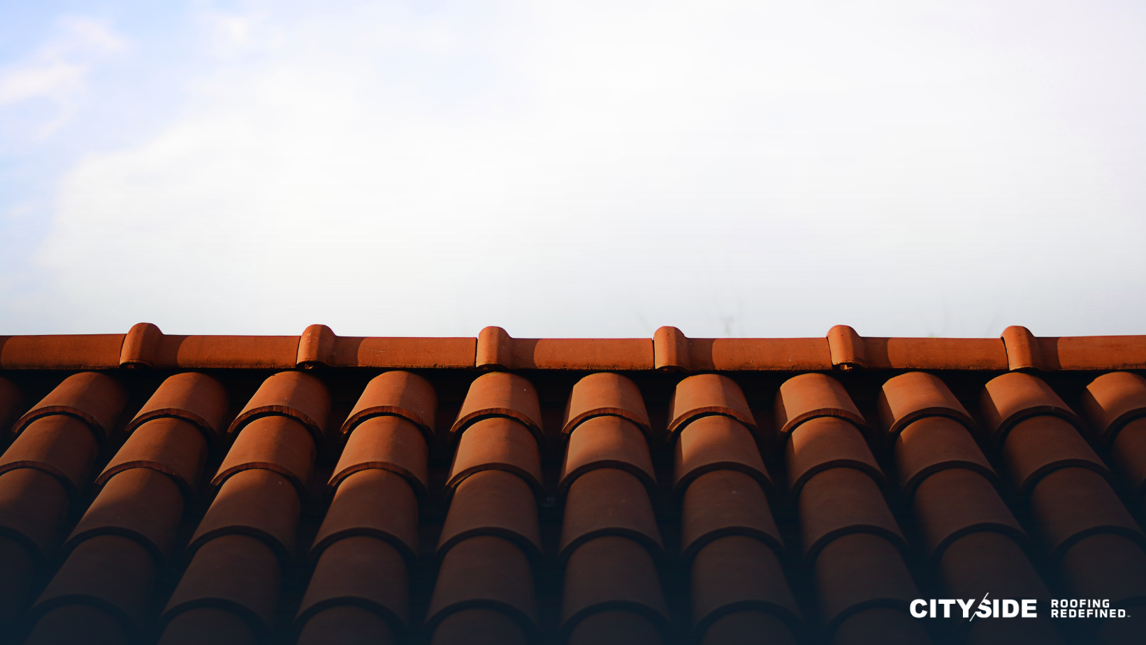 A close-up view of a textured roof with a clear blue sky in the background, showcasing architectural details.