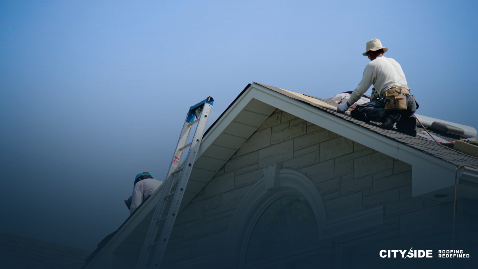 Two men are repairing a house roof, demonstrating teamwork and construction skills under a clear blue sky.