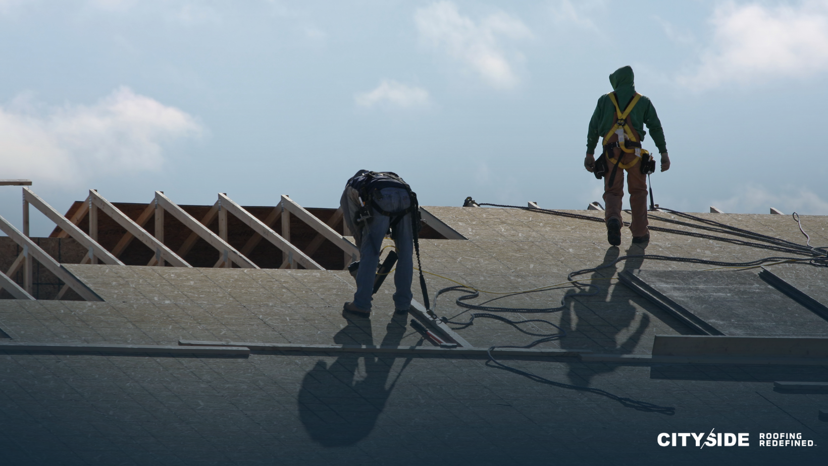 Two men stand on a building's roof, overlooking the city skyline, engaged in conversation