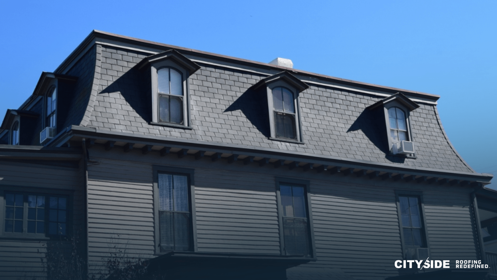 A house featuring a black roof and black windows, set against a clear sky, showcasing a modern architectural design.