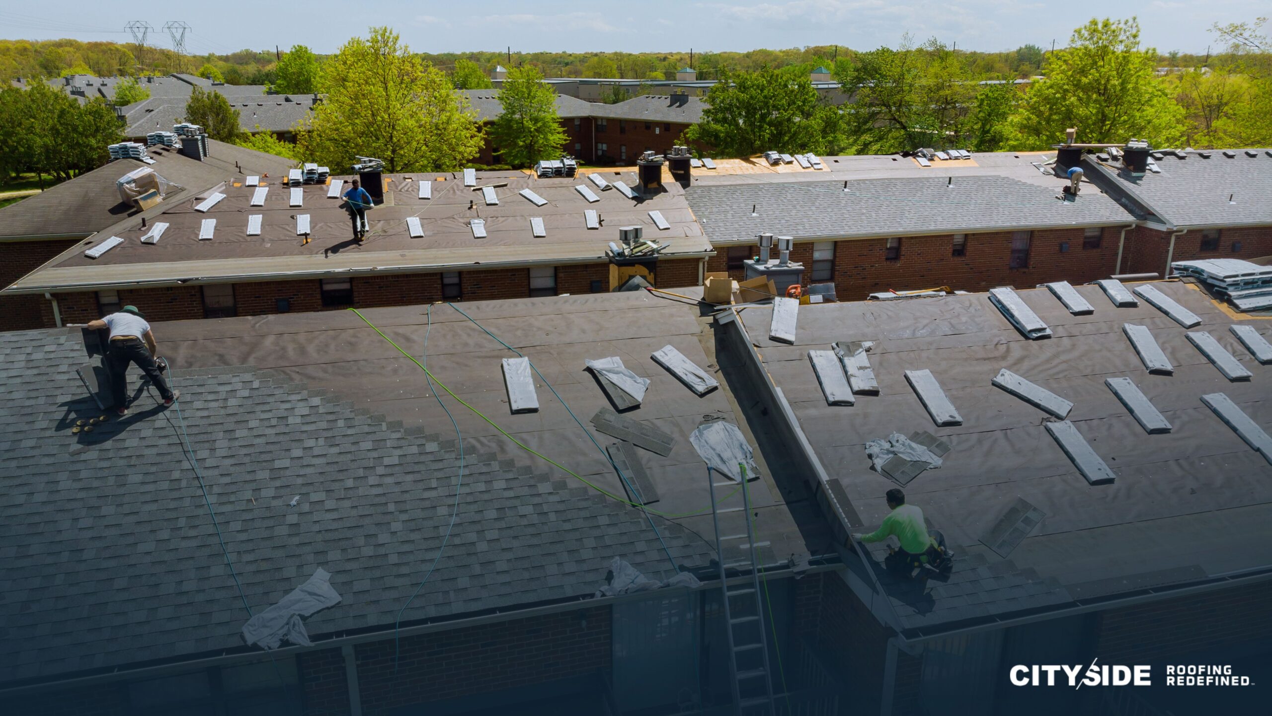 A group of men collaborating on a rooftop, engaged in construction work under clear skies.