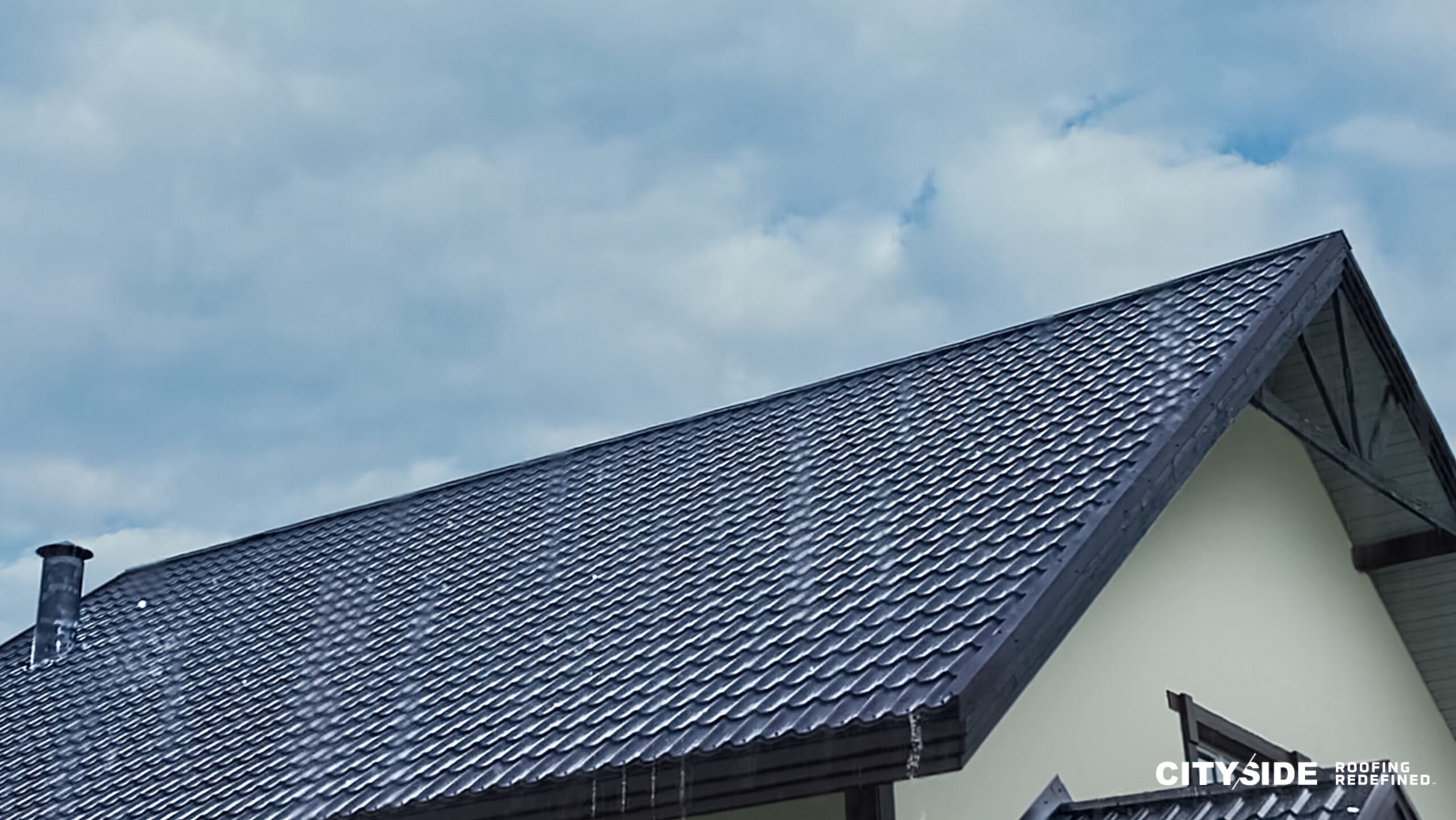 A house featuring a black roof and a white chimney, set against a clear sky, showcasing a classic architectural style.