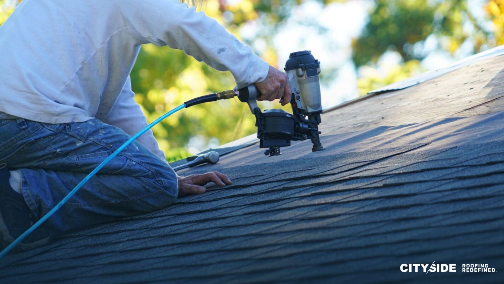 A man uses a nail gun to secure roofing materials,