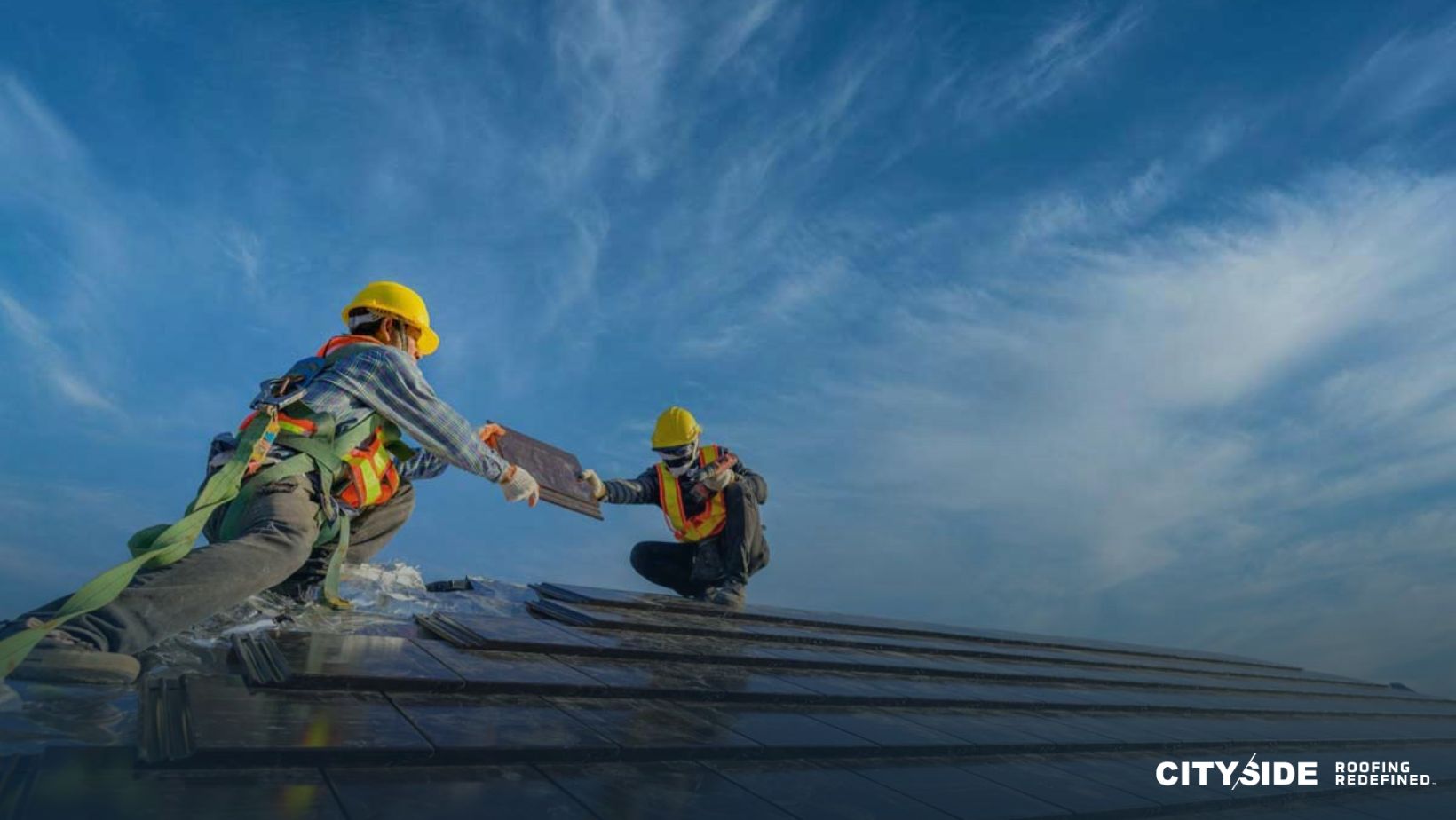 Two men working on a roof under a clear blue sky