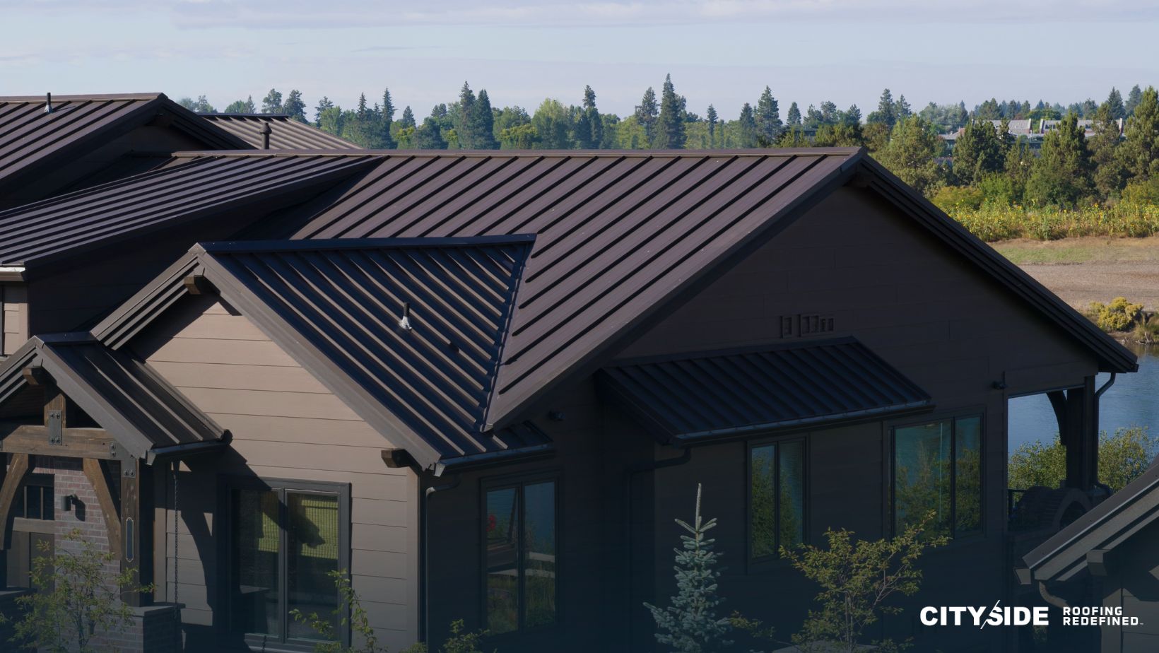 A house with a metal roof stands in front of a serene lake