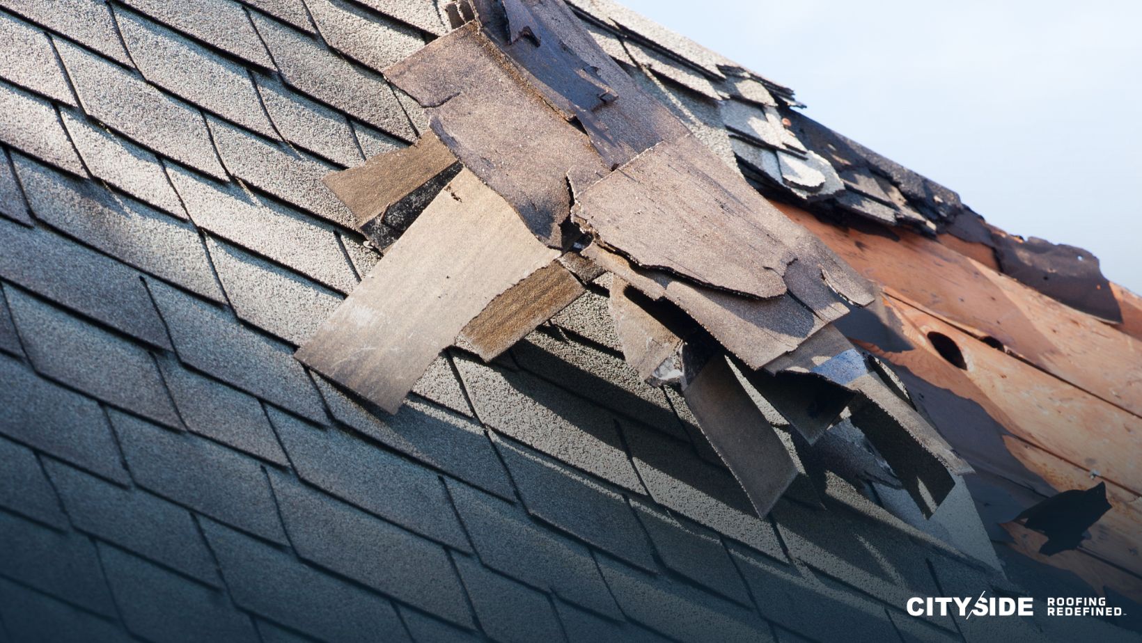 A close-up of a roof showing damaged shingles