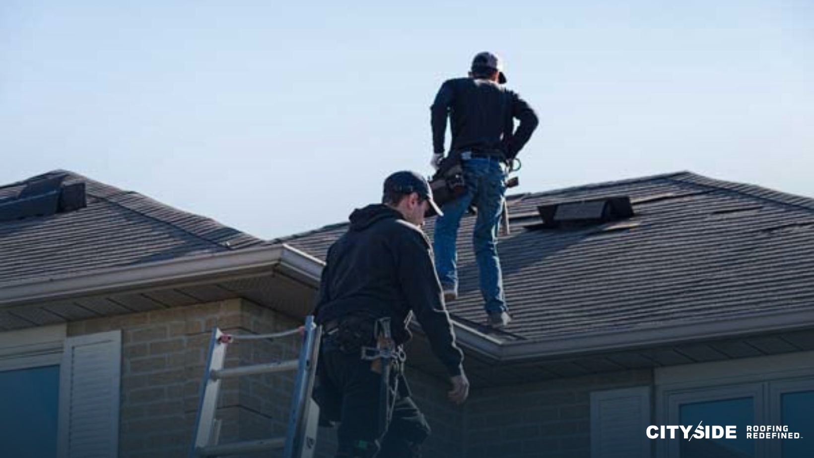 Two men standing on the roof of a house