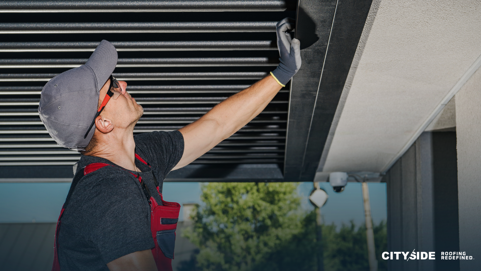 A man wearing a hard hat and gloves repairs a roof