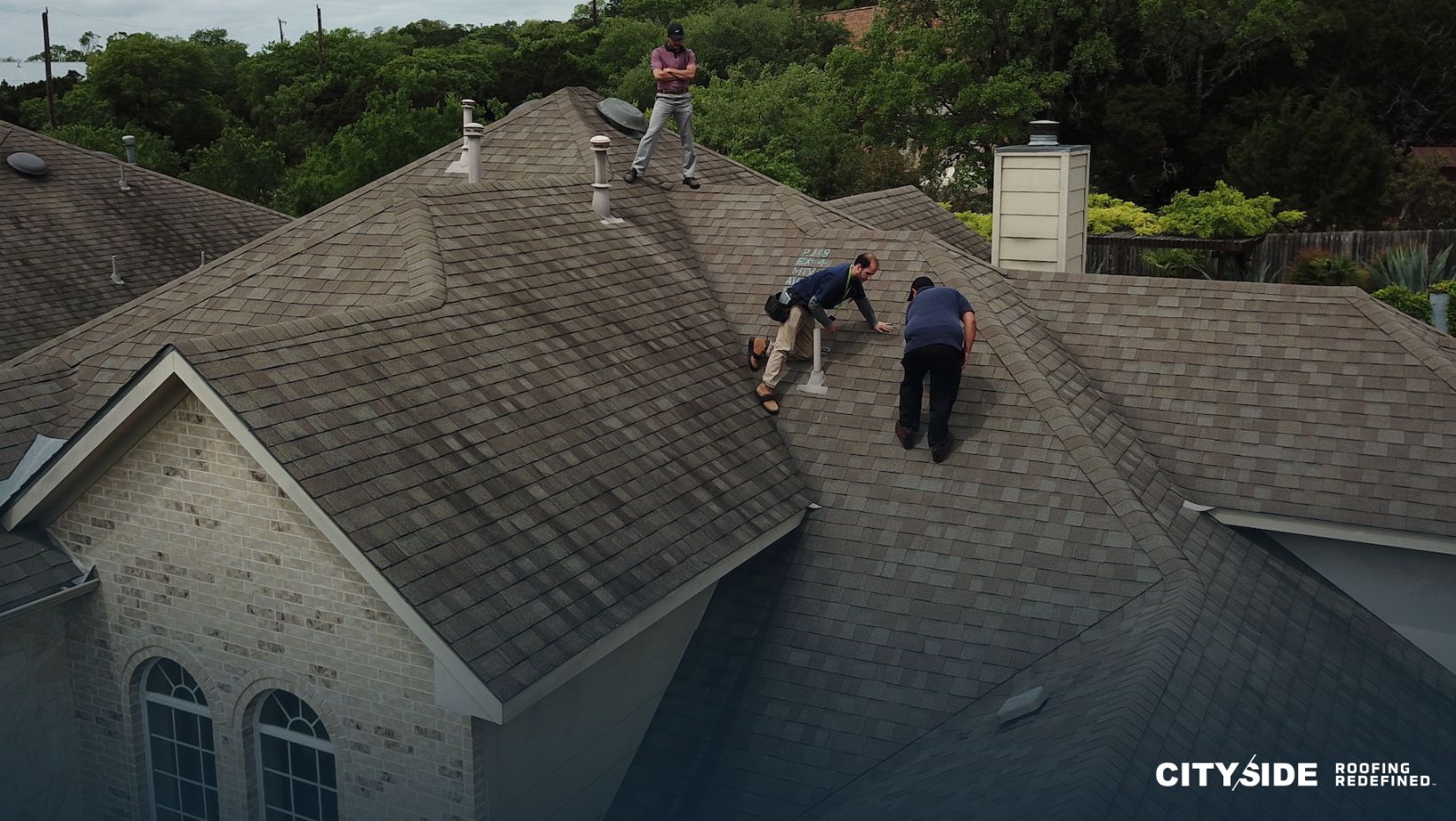 Three men are collaborating on a roof