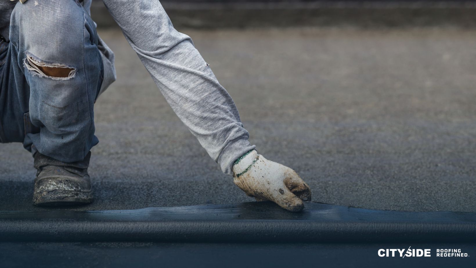 A man is laying a rubber mat on a concrete floor