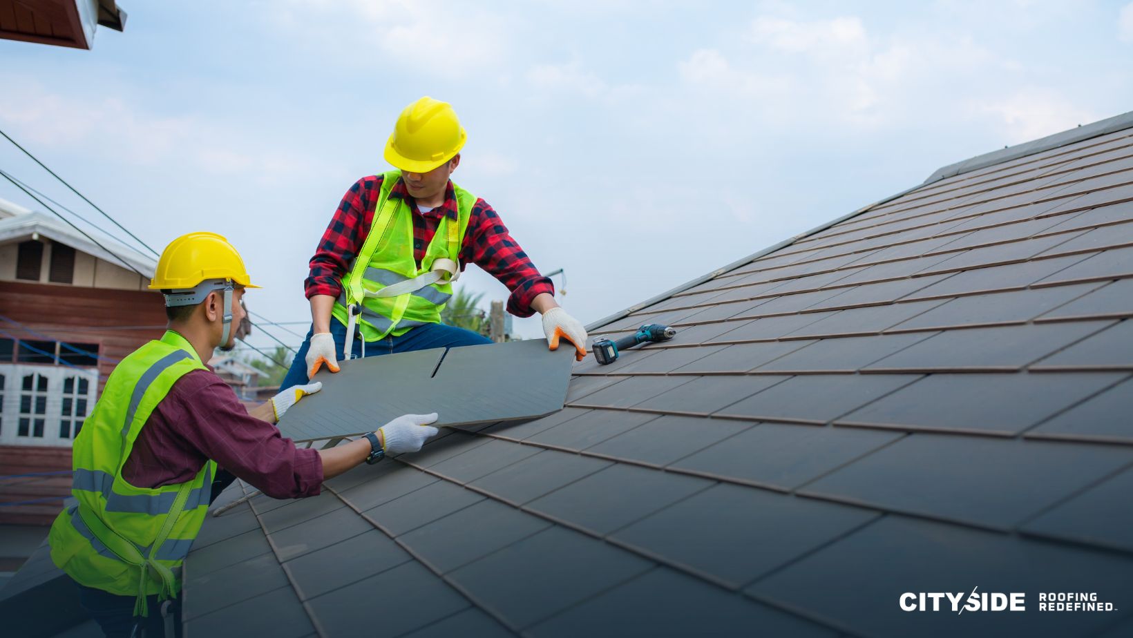 Two men in safety vests working together on a roof