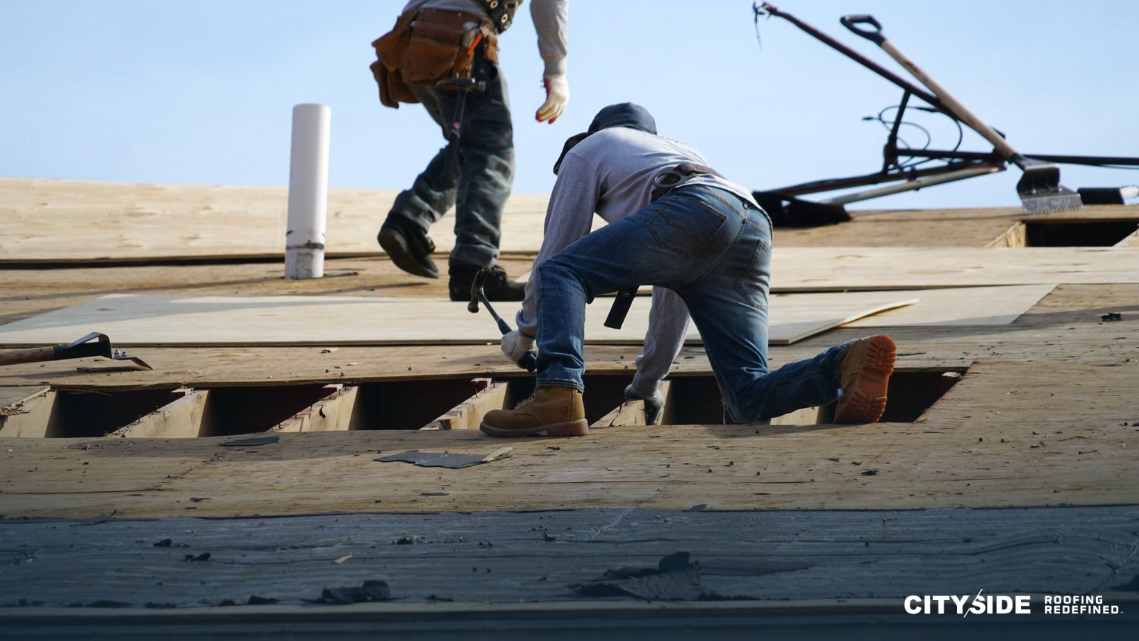 Two men are working on a roof