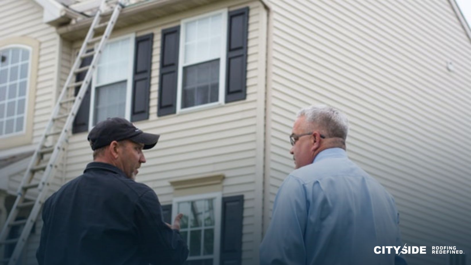 Two men stand outside a house