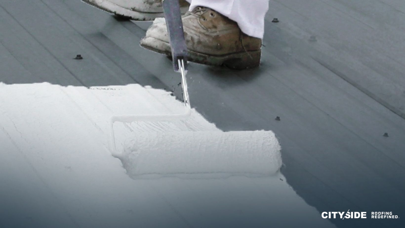 A person painting a roof with a roller