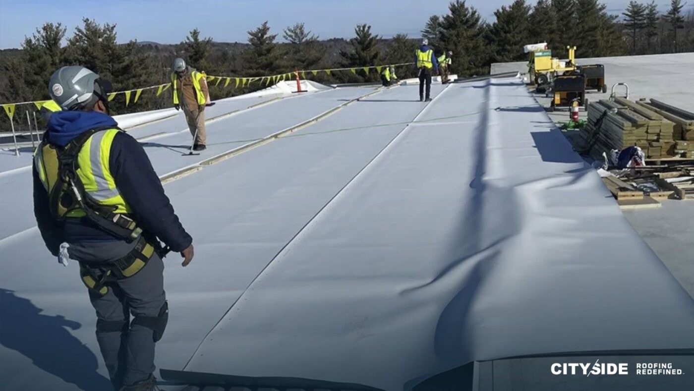 A man in a safety vest is engaged in roofing work
