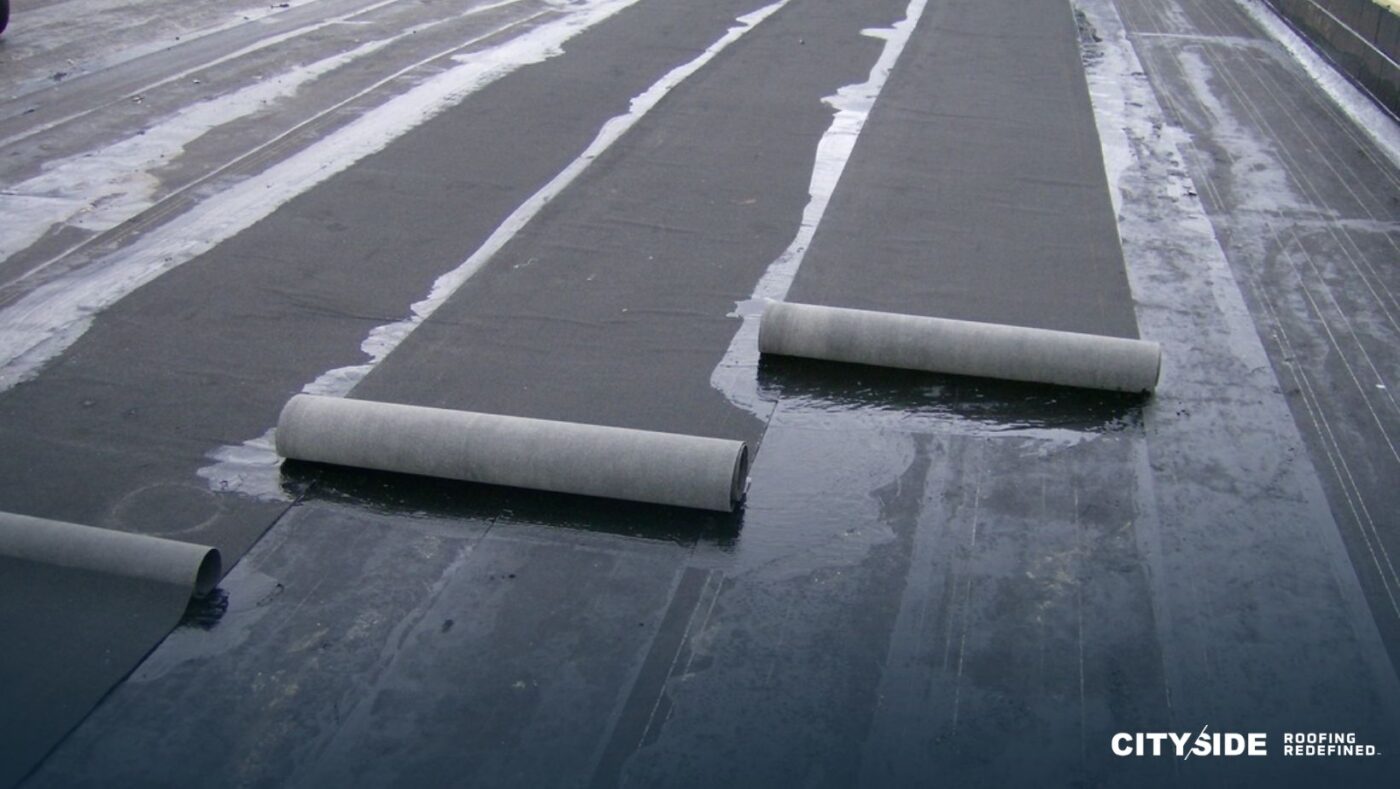 Workers installing a roofing membrane on a flat roof