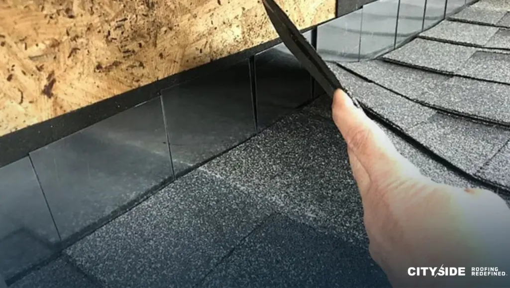 A person cutting shingles on a roof with a knife