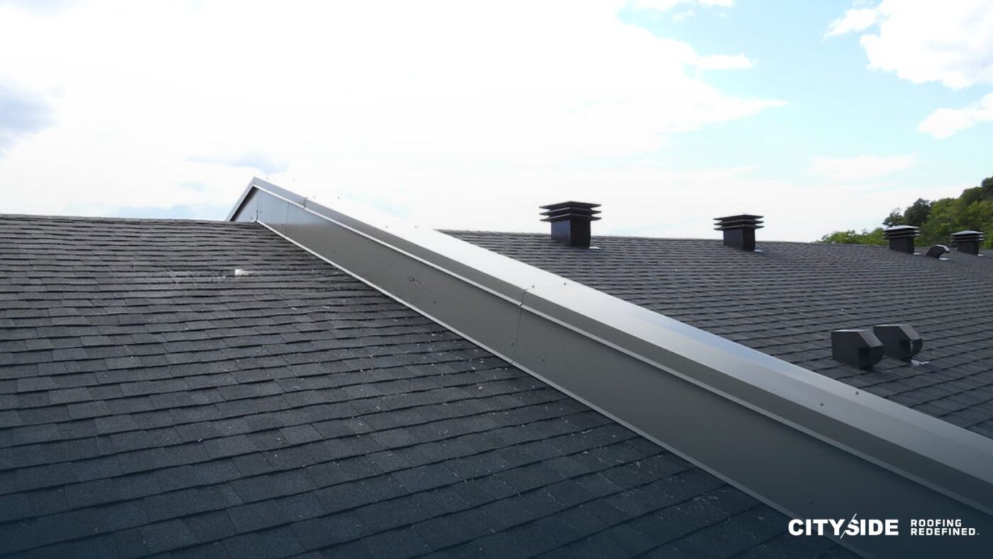 A roof featuring a chimney and a chimney vent against a clear sky