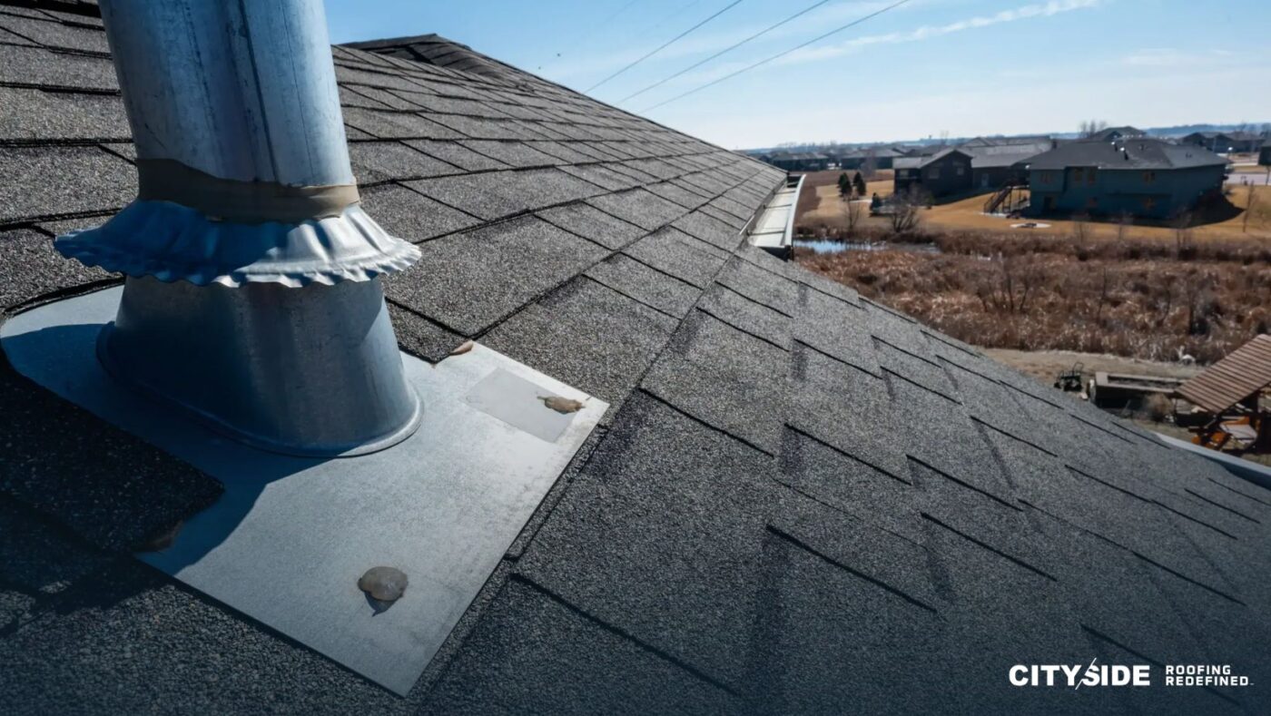 A roof featuring a prominent metal vent positioned on its surface.
