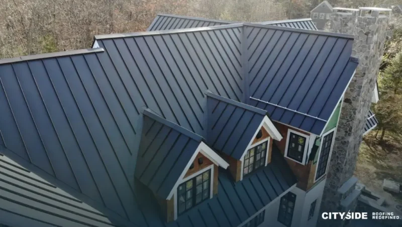 A close-up view of a house roof featuring a sleek, reflective metal surface under clear blue skies