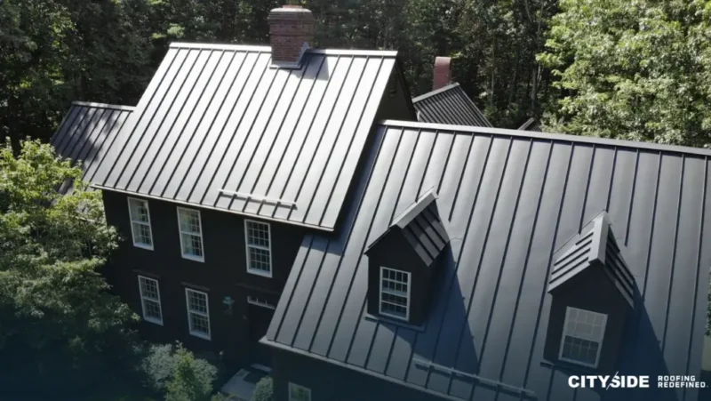 A close-up view of a house roof featuring sleek black metal panels