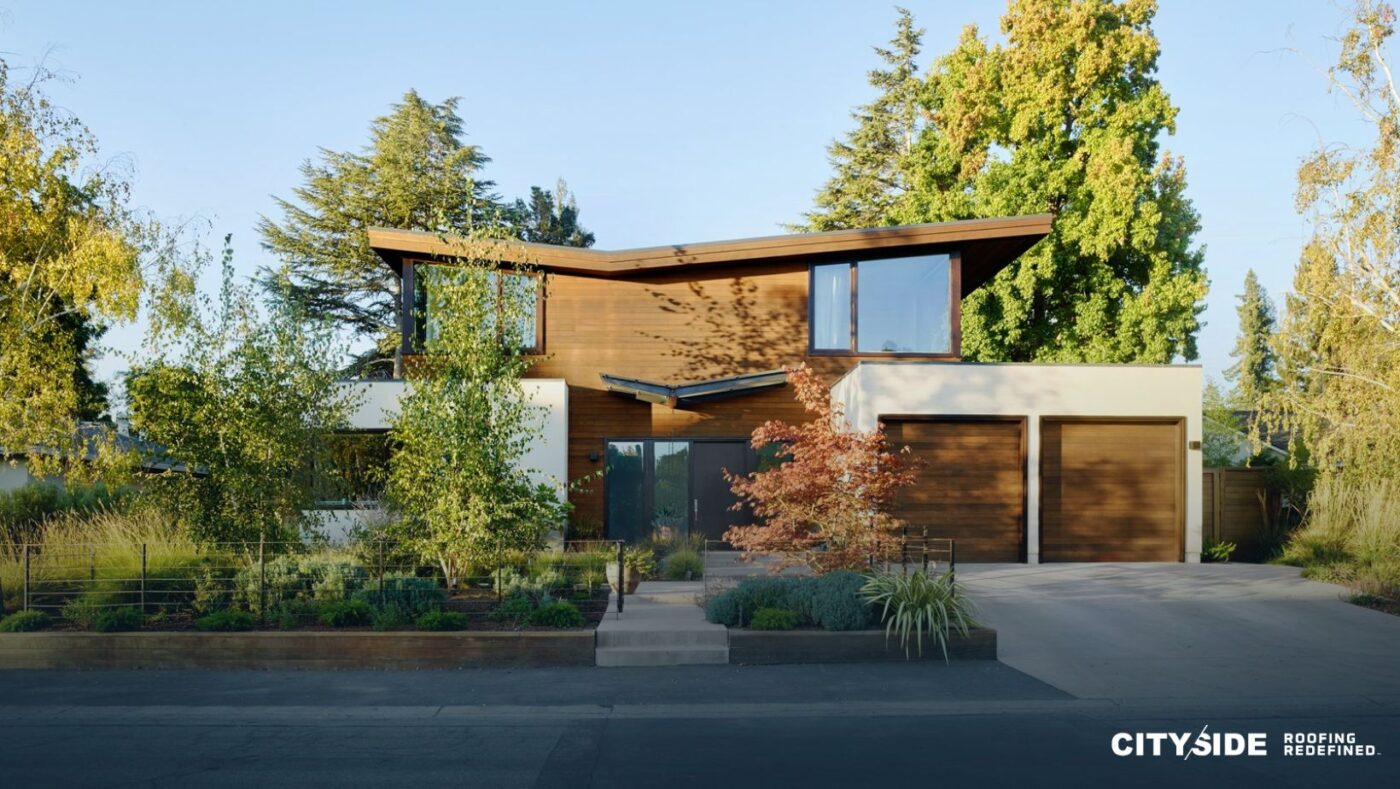 A modern home featuring a spacious driveway surrounded by lush trees.