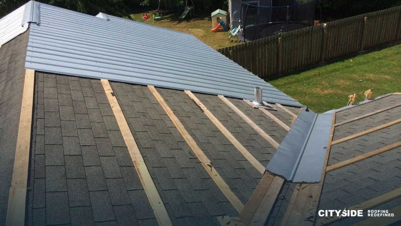 Workers installing metal roofing on a residential building, showcasing tools and materials used in the roofing process.