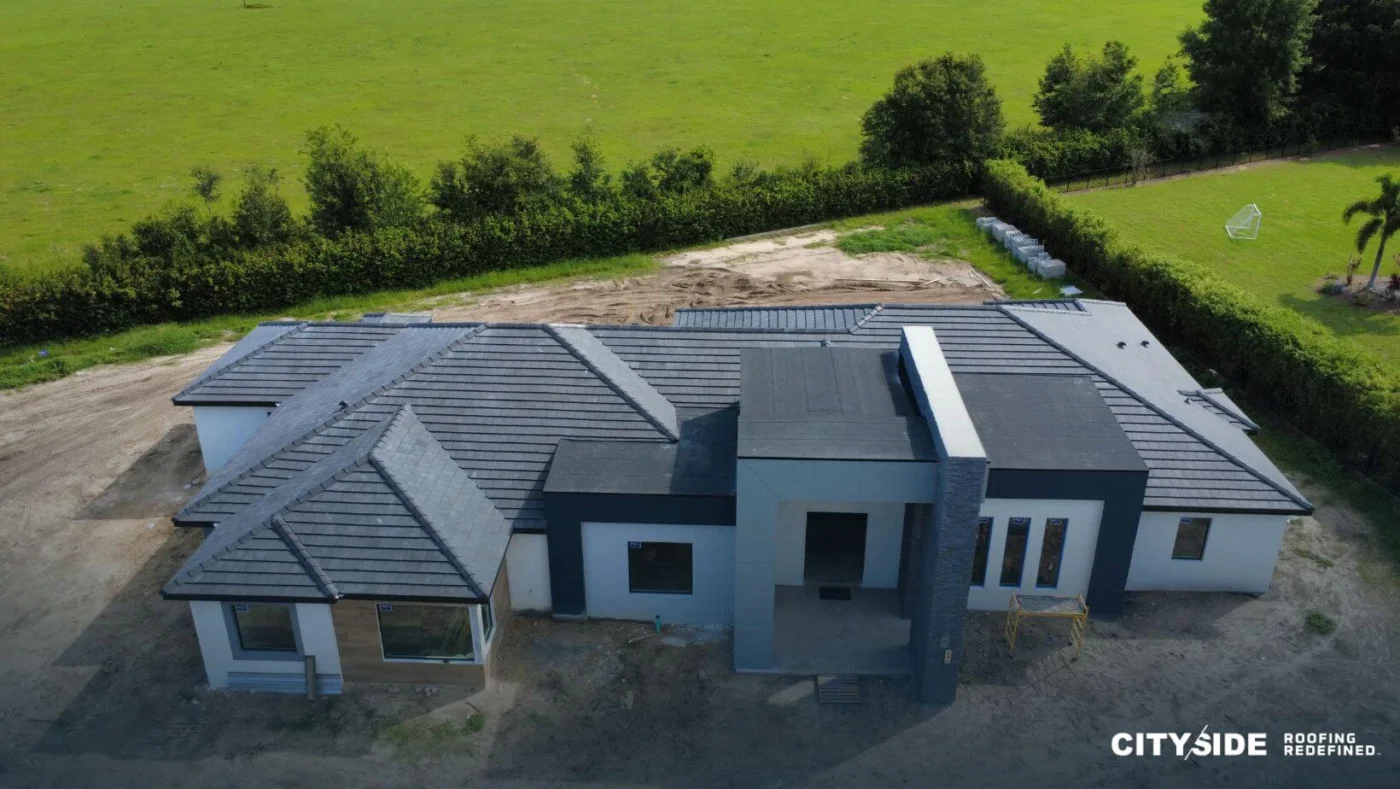 Top-down perspective of a house with a distinct roof, surrounded by greenery.