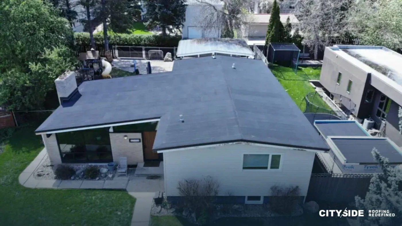 A house featuring a black roof, set against a clear blue sky.