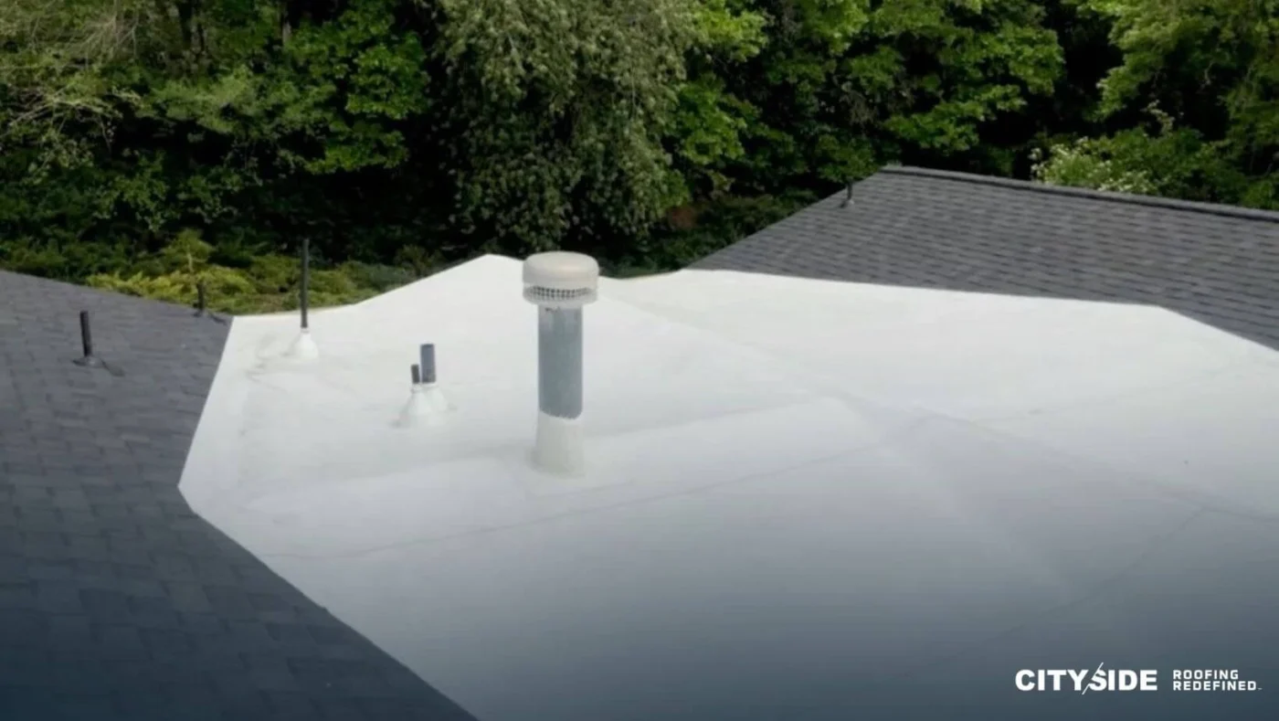 A house roof featuring a prominent chimney at its peak against a clear sky.