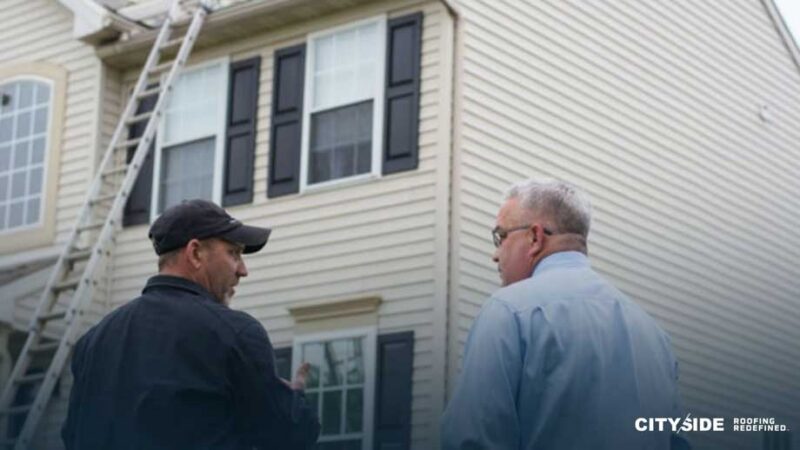 Two men stand outside a house