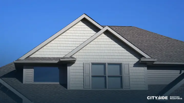 A house with gray siding stands under a clear blue sky, showcasing a serene and inviting atmosphere.