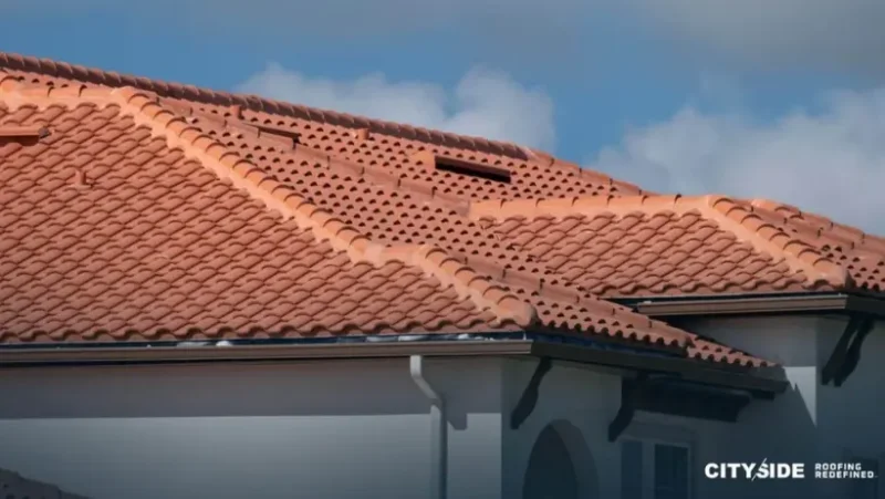 Close-up of a red tile roof, showcasing the texture and color of the tiles against a clear blue sky.