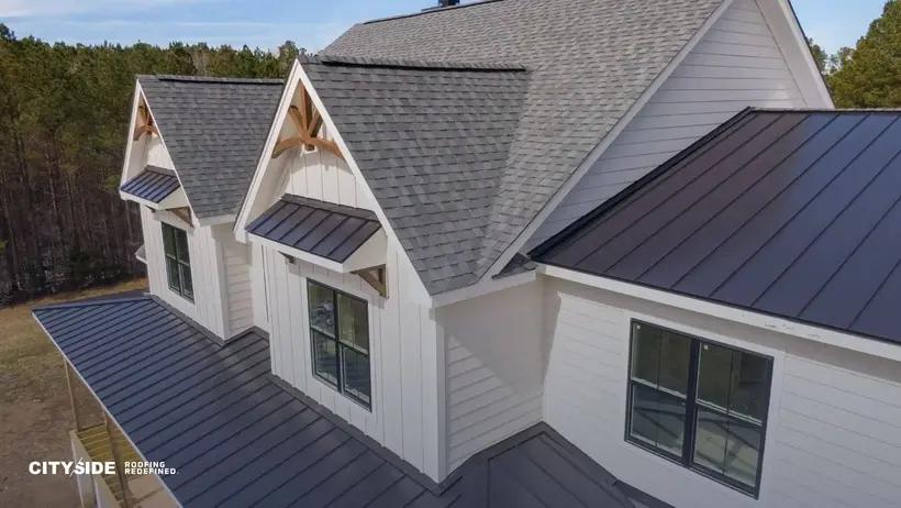 A close-up view of a house roof featuring a sleek, reflective metal surface under clear blue skies.