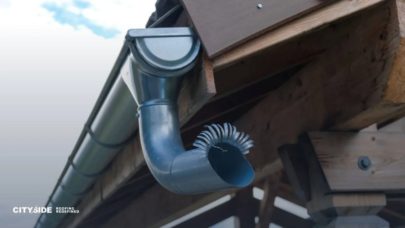 Close-up of a gutter featuring a metal pipe securely attached to its side, showcasing details of the materials used.