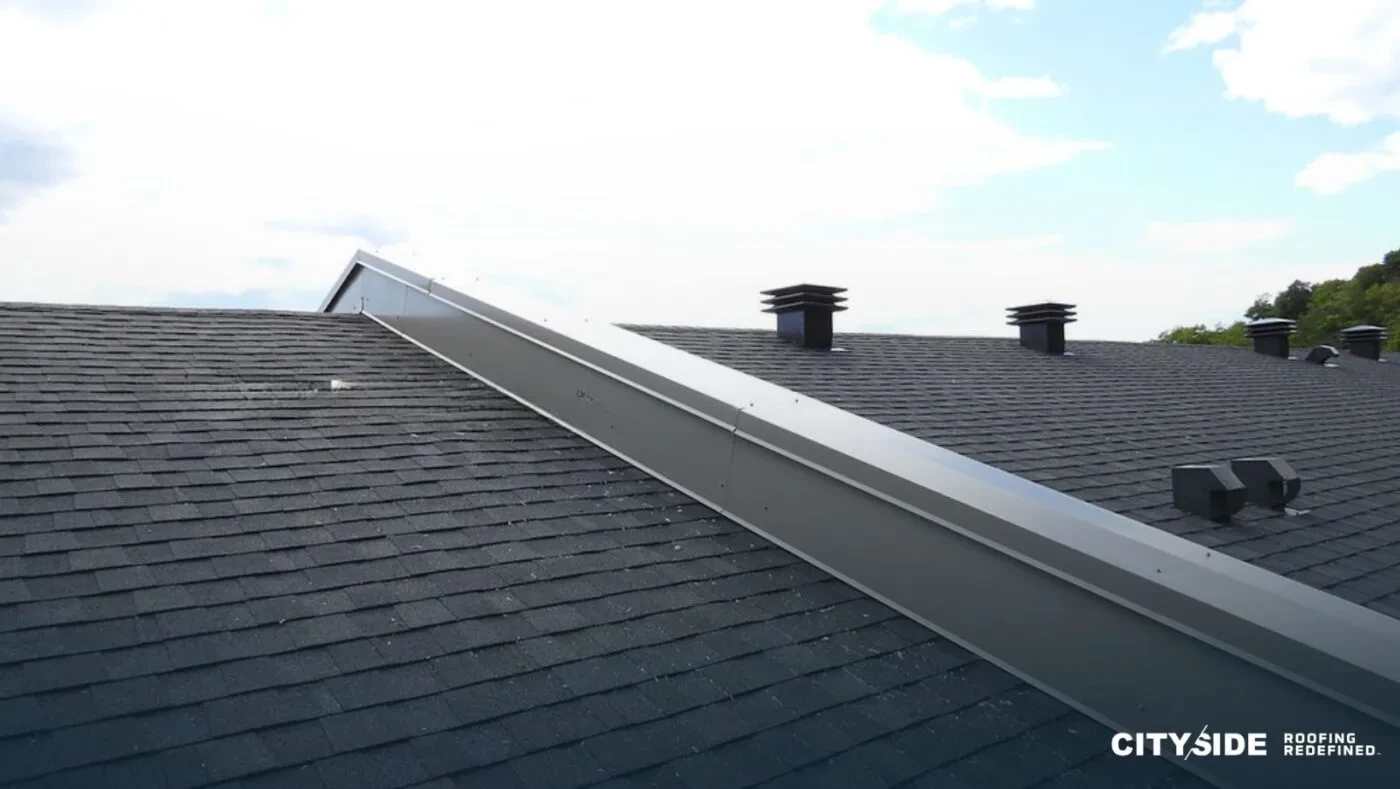 A roof featuring a chimney and a chimney vent against a clear sky