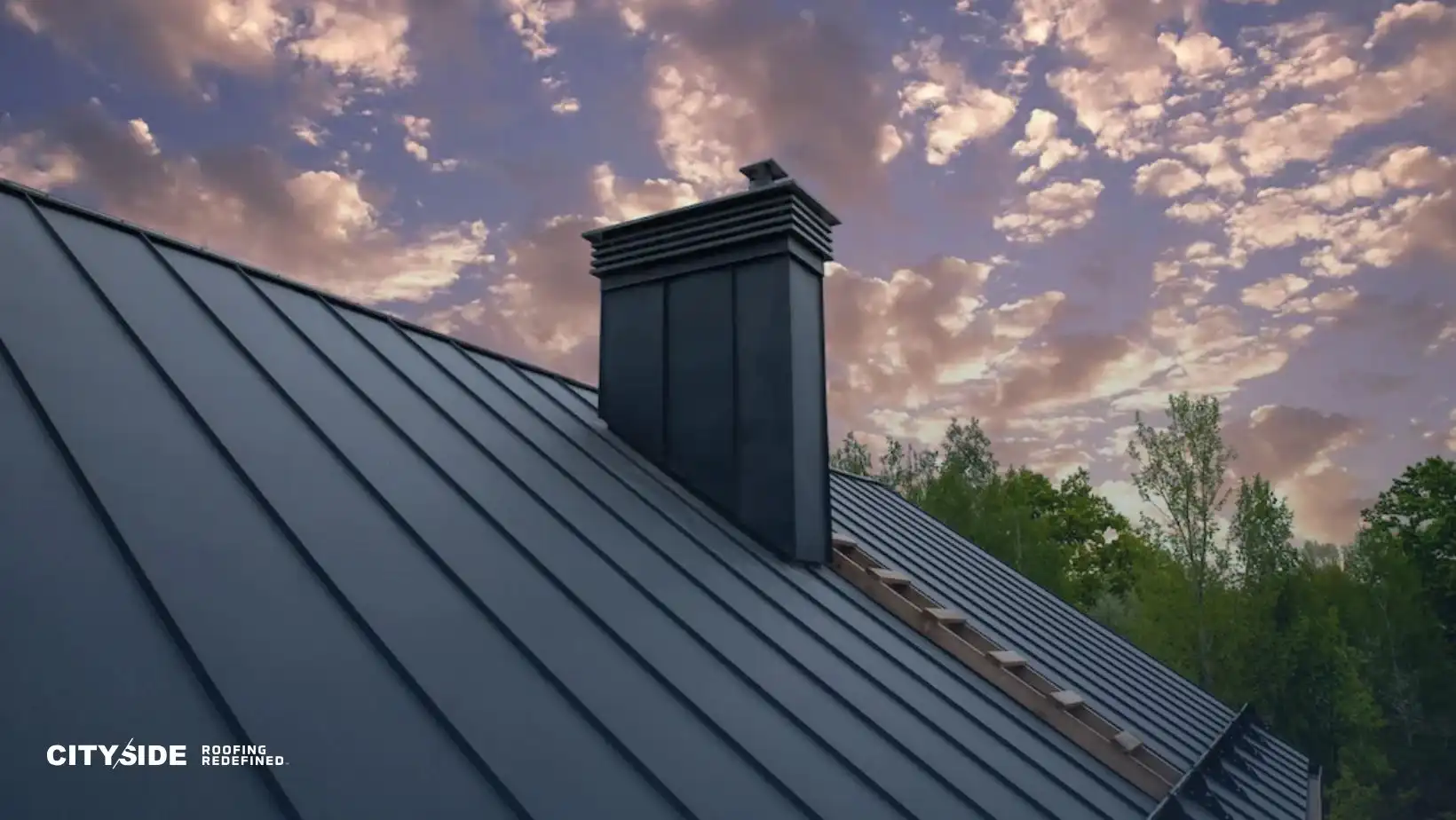 A dark metal roof with a sleek chimney is set against a dramatic, cloud-filled pink and purple sky. Trees are visible in the background. The mood is serene.
