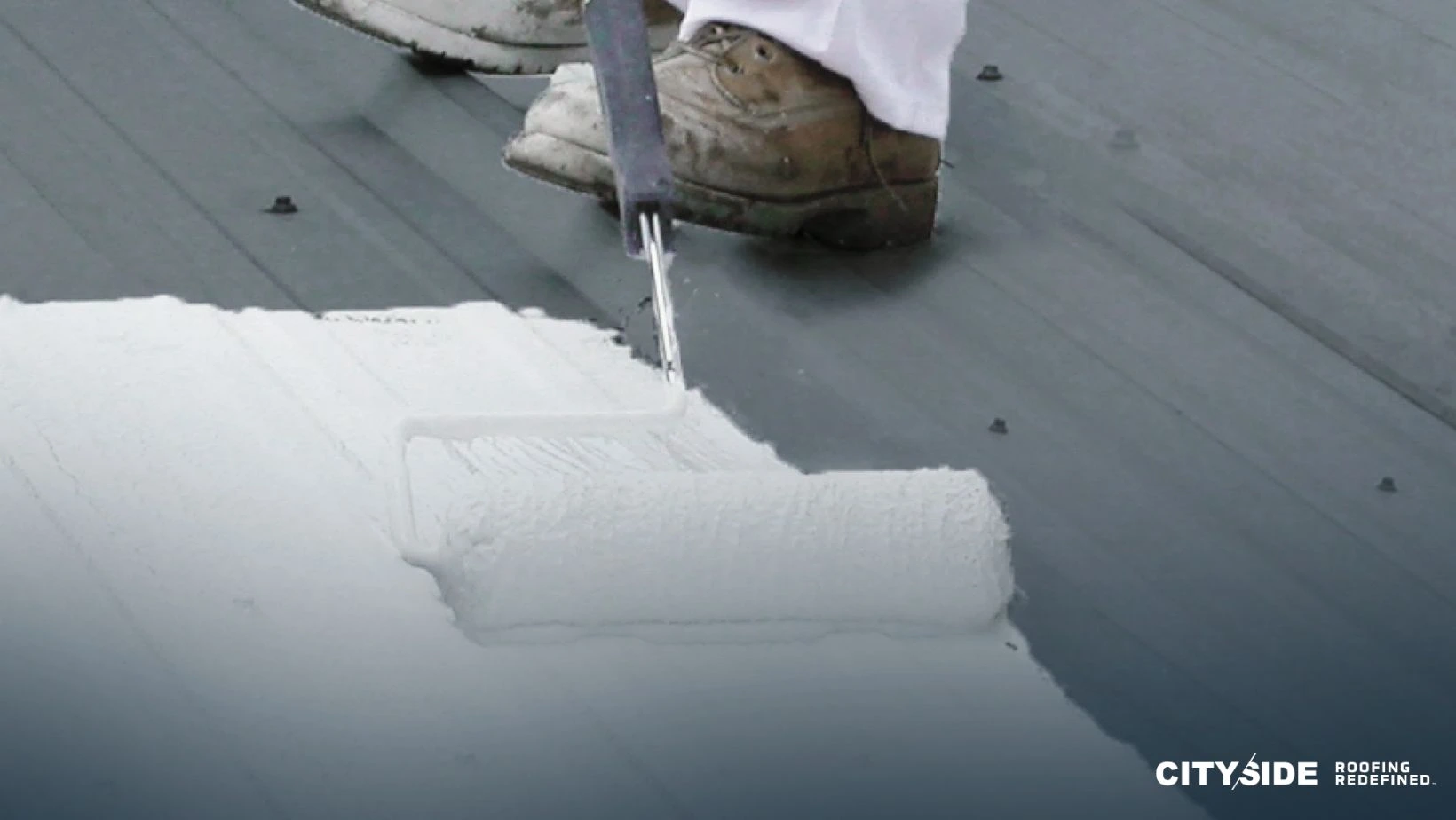 A person painting a roof with a roller
