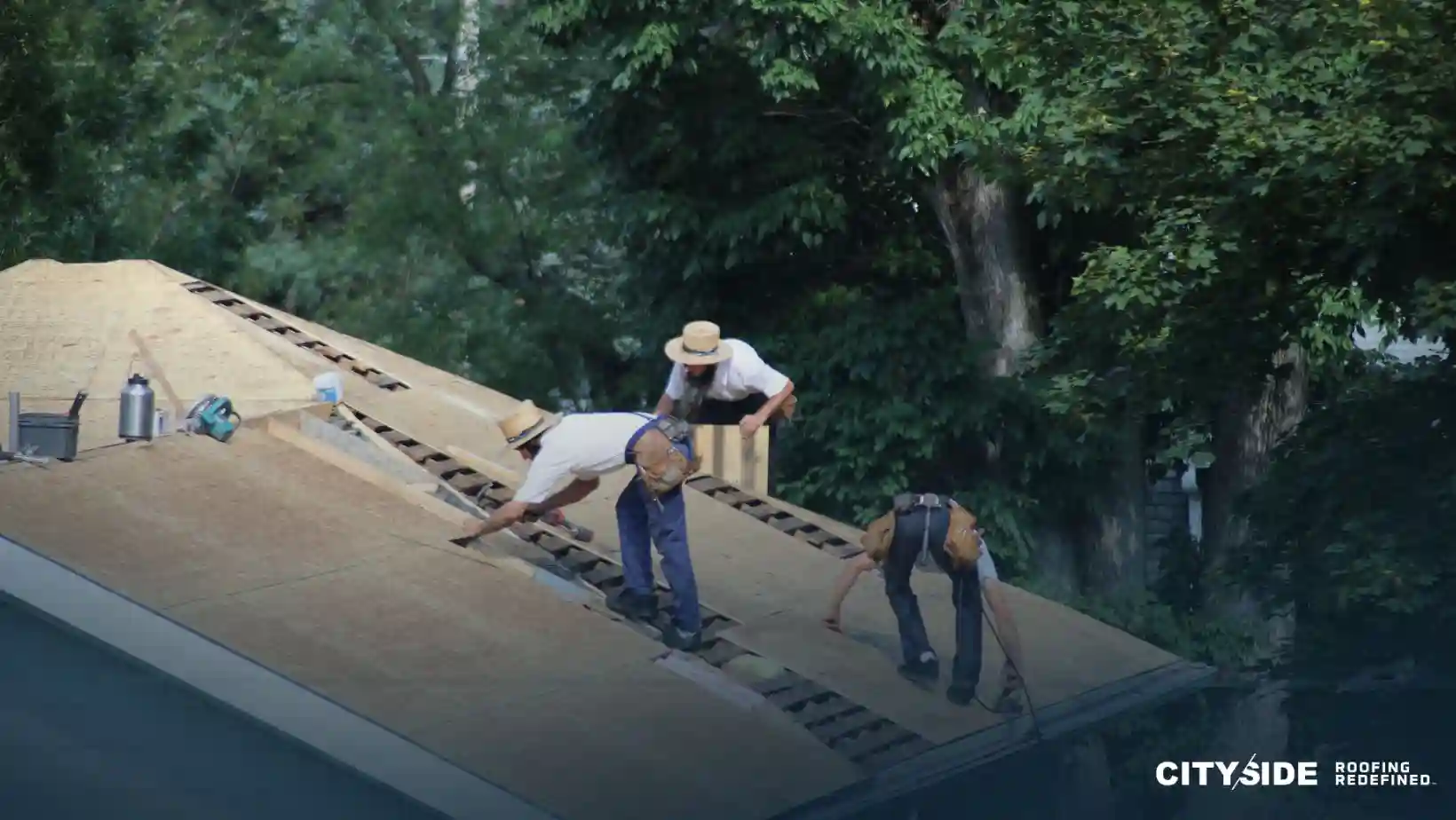 Three men are collaborating on a roof, using a ladder for access and support during their work