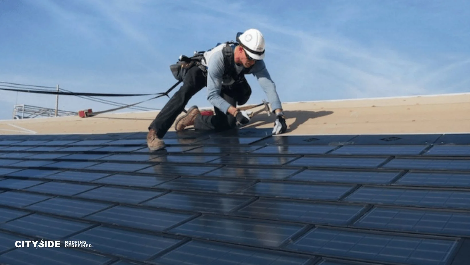 A construction worker in safety gear installs solar panels on a sloped roof under a clear blue sky, conveying progress and innovation.