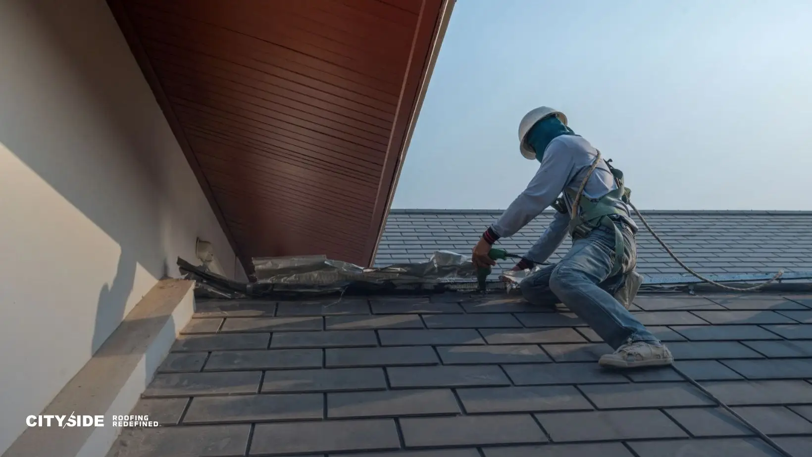A construction worker in safety gear repairs a roof, surrounded by shingles under a clear sky. The tone is industrious and focused. Keywords: roofing, construction.